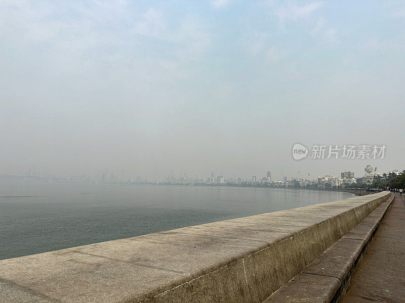 印度孟买的海堤图片，混凝土、海堤防御、海岸管理、防侵蚀、海水、c形长廊、装饰艺术建筑和摩天大楼排列在Girgaon Chowpatty公共海滩上